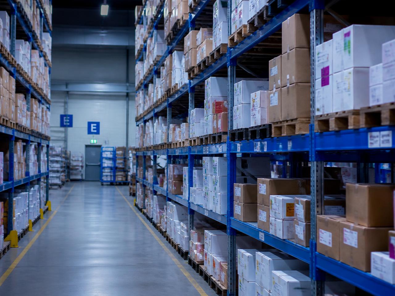 Organised pharmaceutical distribution warehouse aisle with stacked cartons